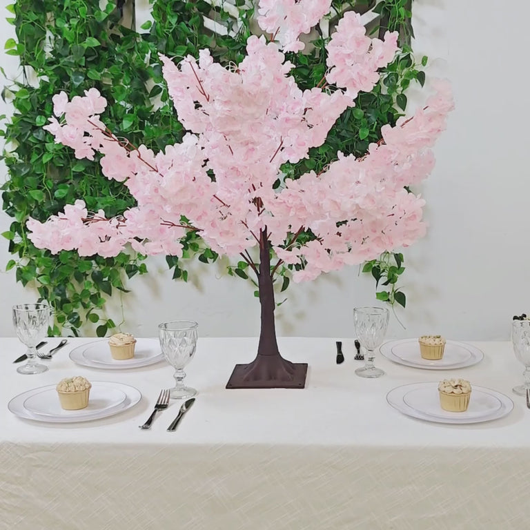 Blush pink artificial cherry blossom tree centerpiece on dining table.