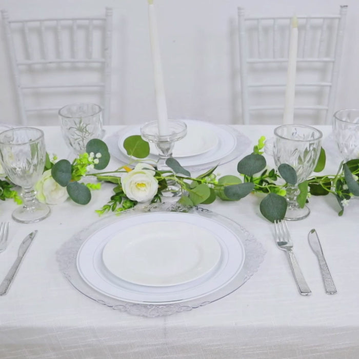 Clear charger plates with silver embossed rim on a decorated dining table.