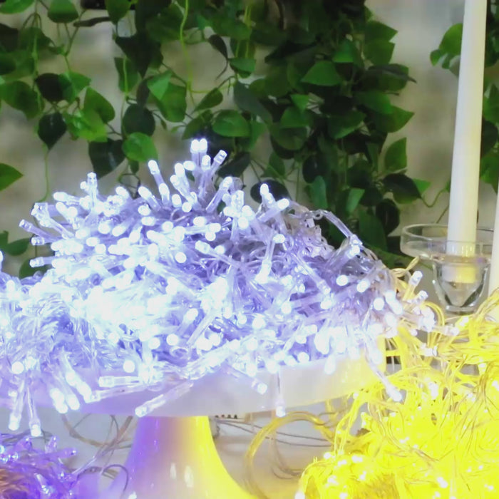Warm white LED curtain string lights on display with greenery backdrop.