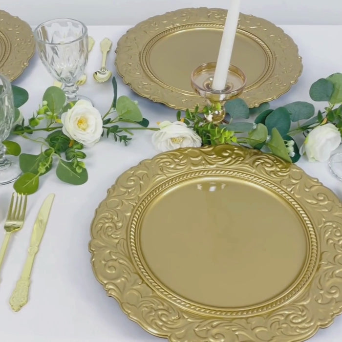 Gold 14" round acrylic charger plates with engraved baroque rim on a table setting.