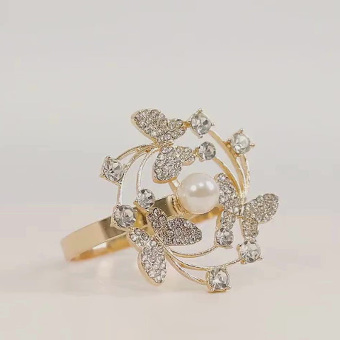 Gold butterfly napkin ring with rhinestones and pearl center for elegant table decor.