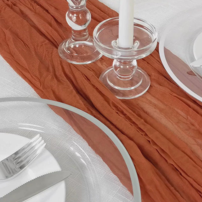 Terracotta gauze cheesecloth table runner on a rustic dining table setting.