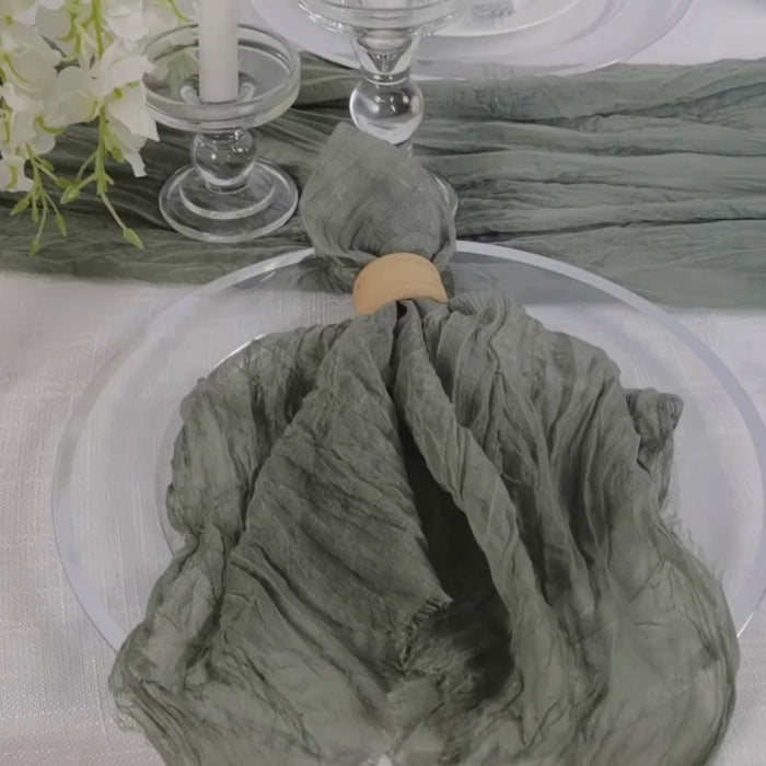 Dusty sage green gauze cheesecloth napkin on a dining table setting.