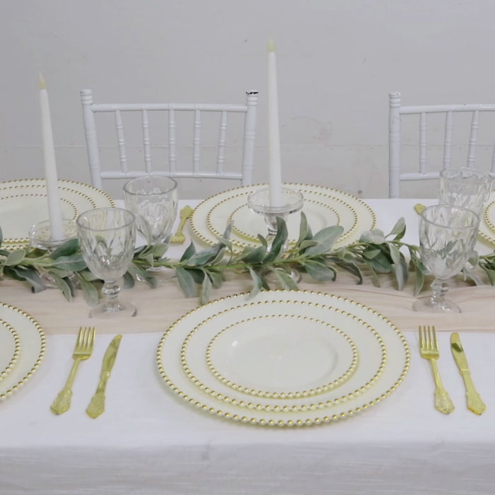 Ivory disposable dinner plates with gold beaded rim on a stylish table setting.
