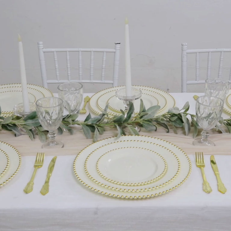 Ivory disposable dinner plates with gold beaded rim on a stylish table setting.
