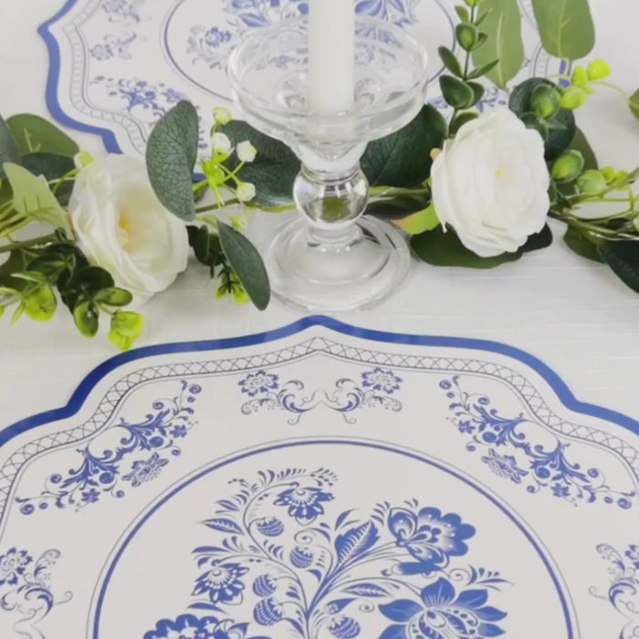 White placemats with blue damask floral pattern and scalloped rim for elegant events.
