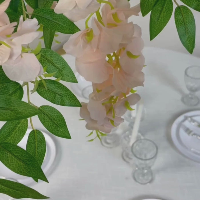 Blush artificial silk wisteria vine hanging canopy with green leaves.