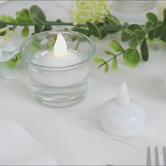 Warm white LED tealight candles in a clear glass holder, floating in water.