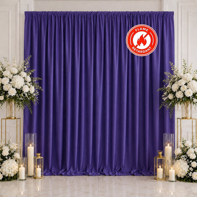 Purple draped wedding backdrop with white floral arrangements and candles