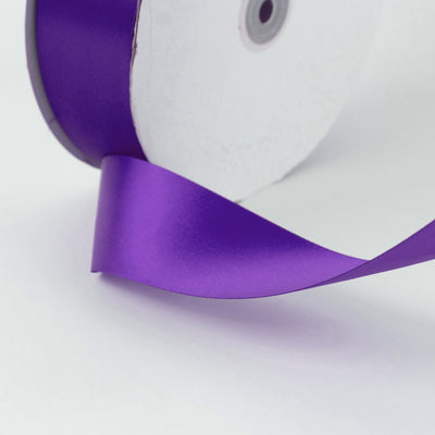 Purple satin ribbon close-up on white background, abstract craft detail