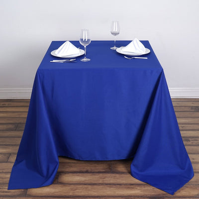 Blue tablecloth set with plates and glasses on a wooden floor.