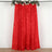 Red textured curtain with floral garland on top, hanging against a plain background.