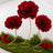 Red artificial flower topiary display with gold stands and green moss backdrop
