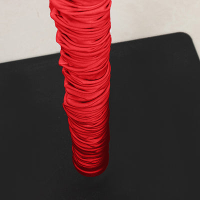 Red ruched fabric wrapped around a vertical pole on a black surface