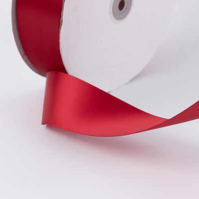 Red satin ribbon on white background, close-up decorative roll