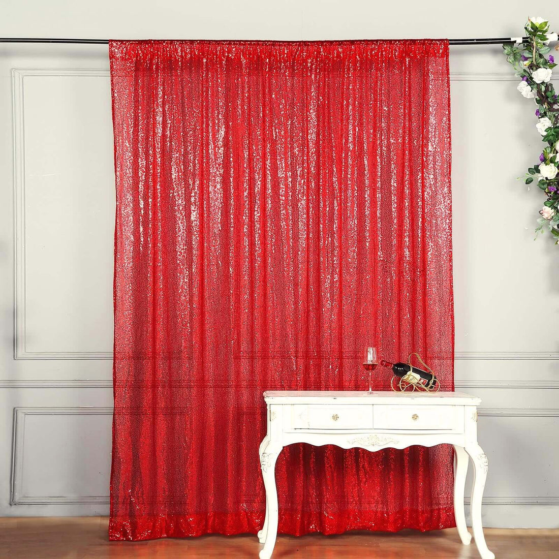 Red shimmering curtain draped elegantly in front of a white table.