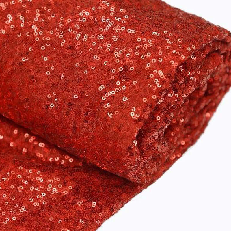 Rolled red sequin fabric with shimmering texture. #whtbkgd