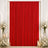 Red velvet curtain backdrop with white floral arrangements and candles