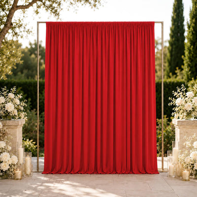 Red wedding backdrop with floral arrangements and candles outdoors