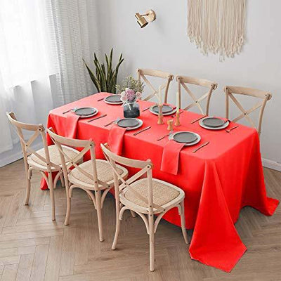 Red tablecloth draped over a dining table set with plates and chairs.