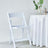 White folding chair next to a table with a plant and decorative items.