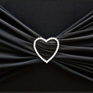 Heart-shaped rhinestone brooch on black fabric.