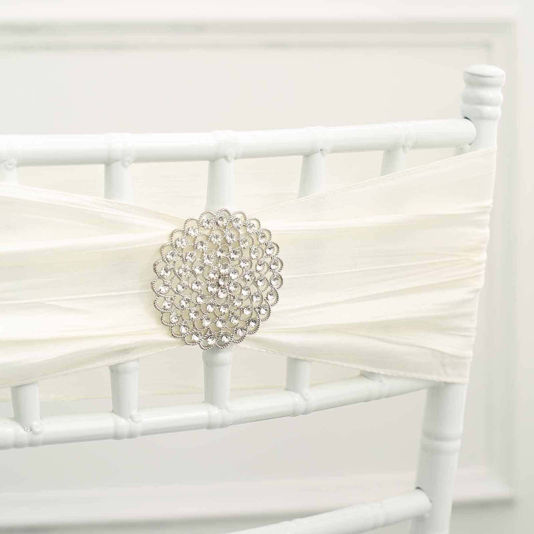 White chair sash with decorative rhinestone embellishment.