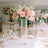 Elegant floral arrangement in a tall glass vase at a beautifully set table.