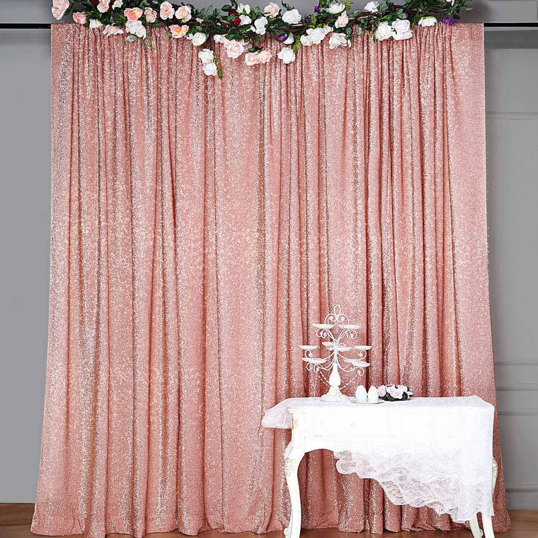 Rose gold sequin backdrop with floral decor and table display.