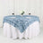 Blue rose tablecloth draped over a round table with wine glasses and flowers.