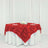 Red rose-patterned tablecloth draped over a round table with white skirt.