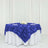 Blue rose-patterned tablecloth draped over a round table with white linens.