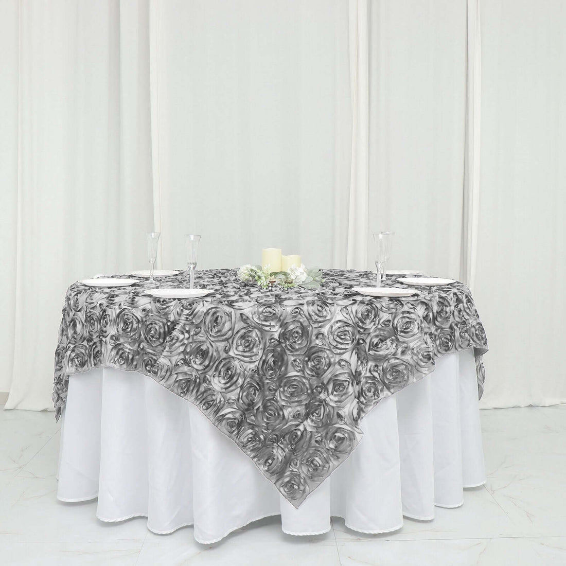 Black and white rose-patterned tablecloth draped over a round table.