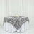 Black and white rose-patterned tablecloth draped over a round table.