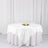 White rose-patterned tablecloth on a round table with candles and floral centerpiece