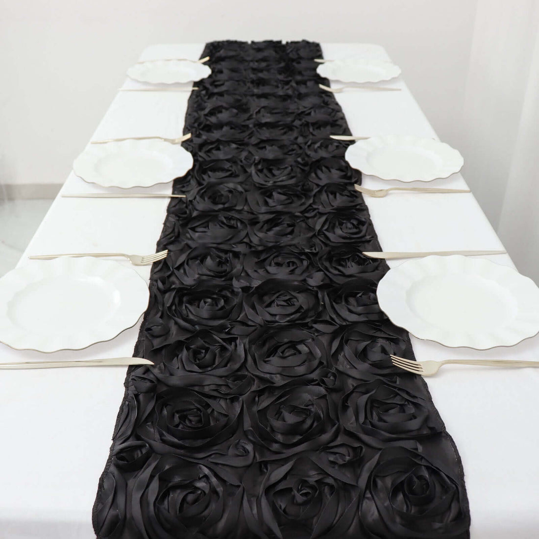 Black rose table runner with white plates set on a dining table.