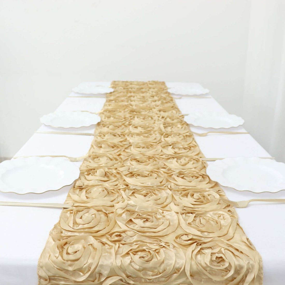 Gold rose table runner on a white table with empty plates.