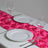 Pink floral table runner with white plates and wine glasses set for dining.