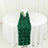 Green rose-patterned table runner on a round white table with flowers and glasses.