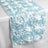 Light blue satin rose table runner on a plain surface.