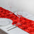 Red rose petal table runner with glassware and plates on a dining table