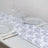 White rose table runner with plates and glasses set for dining.