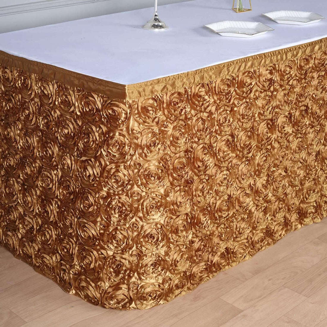 Gold rose-patterned tablecloth draping over a table with a white top.