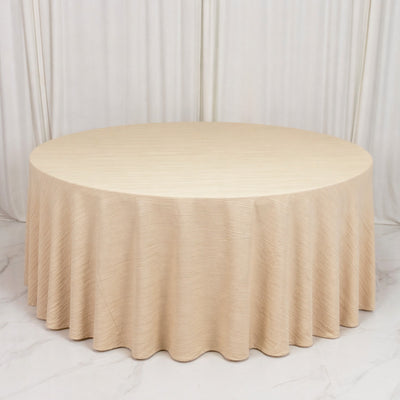 Round beige draped table with pleated skirt on white marble floor
