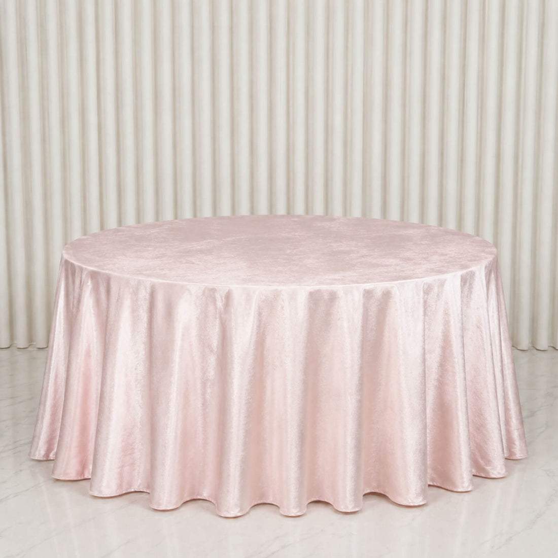 Round blush pink satin tablecloth on a banquet table against draped backdrop