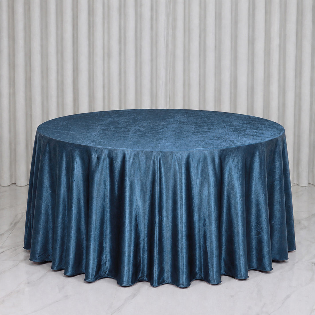Round table with blue satin tablecloth against white curtains