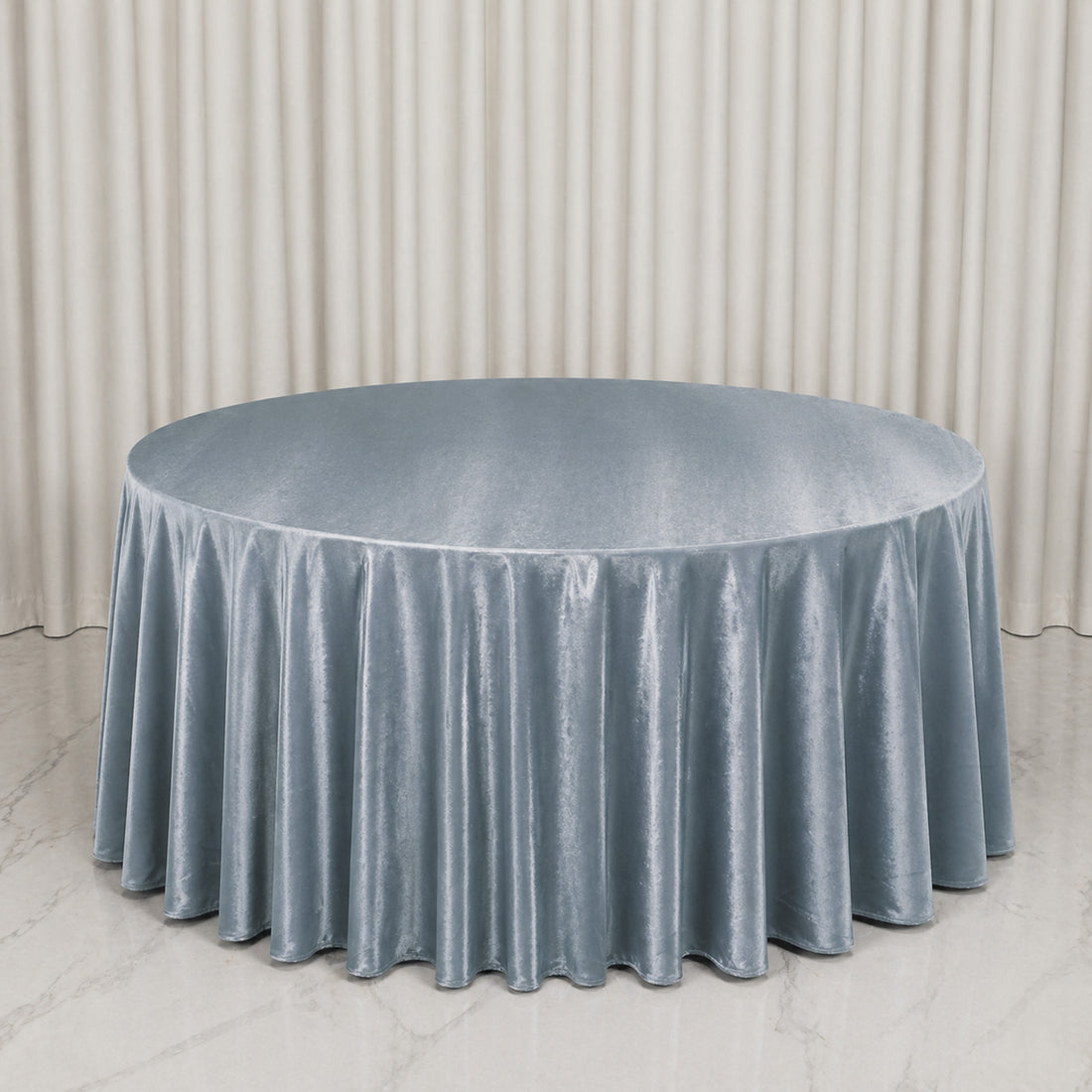 Round table with light blue velvet tablecloth in elegant event setting