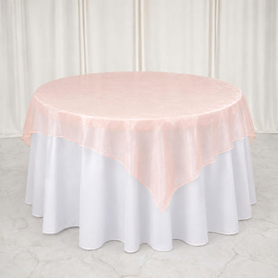 Round table with white tablecloth and blush pink sheer overlay