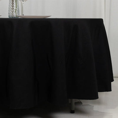 Black tablecloth draping over a round table in a dining setting.