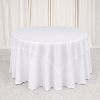 Round white table with elegant layered tablecloth in a minimalist setting